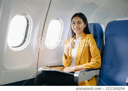 Young Asian executive excels in first class, multitasking with digital tablet, laptop and smartphone. Travel in style, work Young Asian executive excels in first class, multitasking with digital tablet, laptop and smartphone. Travel in style, work 121109204