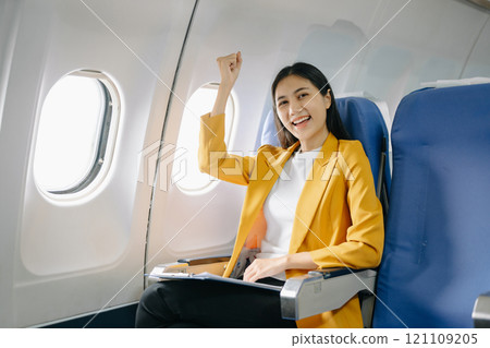 Young Asian executive excels in first class, multitasking with digital tablet, laptop and smartphone. Travel in style, work 121109205