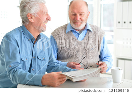 Two elderly men drinking coffee and reading newspaper Two elderly men drinking coffee and reading newspaper 121109346