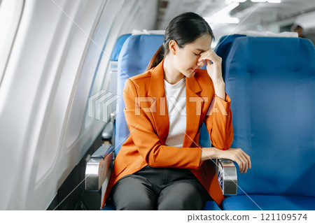 Photo of a frustrated woman sitting on an airplane with her head in her hands. Asian woman sitting 121109574