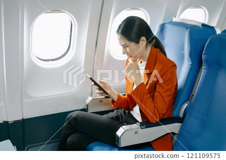 Photo of a frustrated woman sitting on an airplane with her head in her hands. Asian woman sitting 121109575