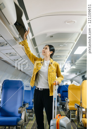 ttractive Asian female passenger of airplane sitting in comfortable seat while working laptop and tablet in style, work with grace. 121109651