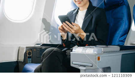 Attractive Asian female passenger of airplane sitting in comfortable seat while working laptop and tablet with mock up area using wireless connection. Attractive Asian female passenger of airplane sitting in comfortable seat while working laptop and tablet with mock up area using wireless connection. 121110309