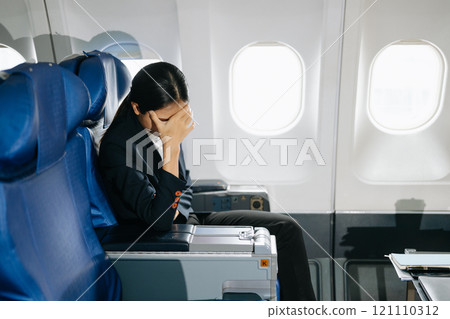 Photo of a frustrated woman sitting on an airplane with her head in her hands. Asian woman sitting 121110312