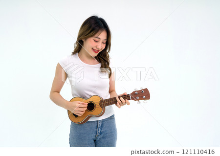 Young asian woman in white t-shirt and jean playing an Ukulele guitar. Portrait on white background with studio light. 121110416
