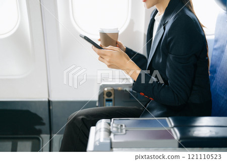 Attractive Asian female passenger of airplane sitting in comfortable seat while working laptop and tablet with mock up area using wireless connection. Attractive Asian female passenger of airplane sitting in comfortable seat while working laptop and tablet with mock up area using wireless connection. 121110523