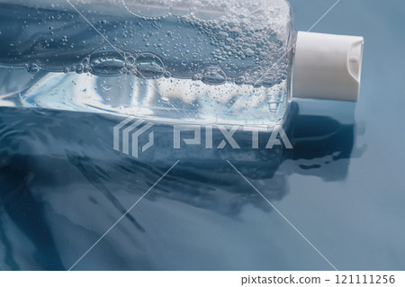 Bottle with cosmetic gel for face and body on blue background in water. 121111256