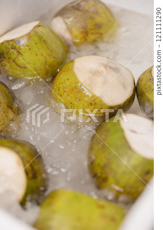 Fresh green coconuts chilled in ice, highlighting tropical street food culture Fresh green coconuts chilled in ice, highlighting tropical street food culture 121111290