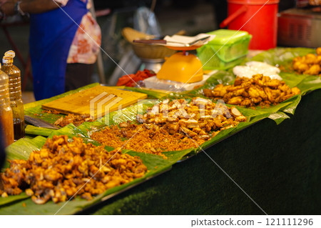 Authentic Thai street food displayed on banana leaves at a bustling market Authentic Thai street food displayed on banana leaves at a bustling market 121111296
