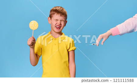 Doctor doing vaccination to crying little boy with sweet candy in hand against pastel blue background. Save of viruses. 121111588