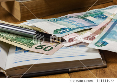 On the open diary page there are money bills and fountain pen 121111972