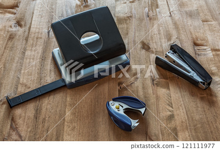 Puncher, stapler and anti-stapler on a wooden surface Puncher, stapler and anti-stapler on a wooden surface 121111977