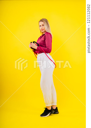 Sports woman in fashion sportswear exercising with elastic band in studio 121112082