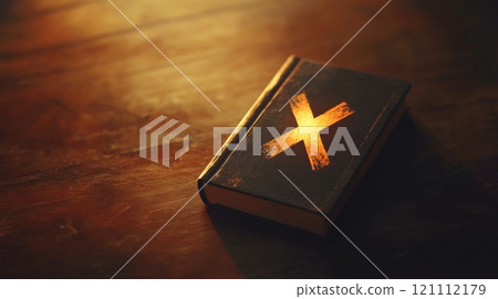Glowing cross illuminating ancient book on wooden table 121112179