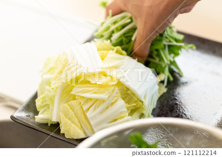一個男人的手把大白菜和水菜放在盤子上 一個男人的手把大白菜和水菜放在盤子上 121112214
