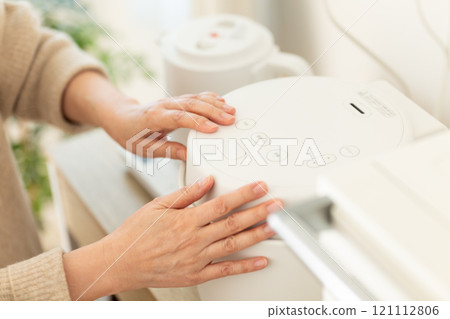 The hands of a middle-aged woman cooking rice in a rice cooker The hands of a middle-aged woman cooking rice in a rice cooker 121112806