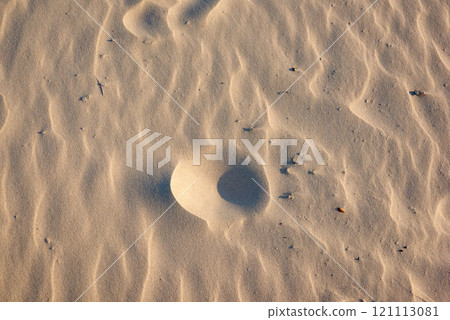 Beach sand. Closeup of sand texture on a beach in summer as background. Brown desert pattern from tropical beach. Desert sand dunes texture. Rippled shore with tiny stones. Beach sand. Closeup of sand texture on a beach in summer as background. Brown desert pattern from tropical beach. Desert sand dunes texture. Rippled shore with tiny stones. 121113081