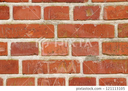 Carved writing on a solid red brick wall of a house or home. Closeup of rough texture and detail background with copyspace on brickwork. Modern architecture and masonry on the boundary of a building 121113105