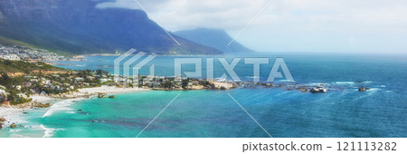 A peaceful view of the Clifton ocean at the Atlantic seaboard with an island and mountains in the background. A city surrounded by blue fresh water and a foggy cloudy sky with copy space. A peaceful view of the Clifton ocean at the Atlantic seaboard with an island and mountains in the background. A city surrounded by blue fresh water and a foggy cloudy sky with copy space. 121113282