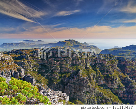 Copy space with scenic landscape at the peak of Table Mountain in Cape Town with cloudy blue sky background. Breathtaking and magnificent views of the beauty in nature after a hike up a rocky region 121113457