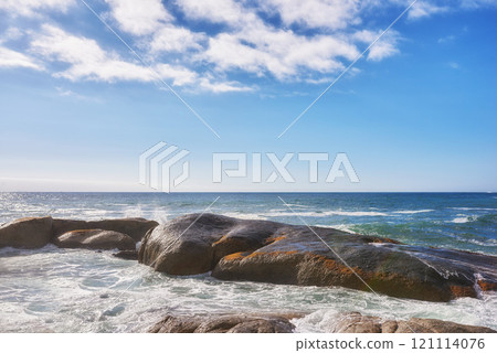 Landscape of large rocks in the ocean with a cloudy blue sky and copy space. Sea waves splashing against boulders on popular Camps Bay beach in Cape Town, South Africa. A beautiful summer destination Landscape of large rocks in the ocean with a cloudy blue sky and copy space. Sea waves splashing against boulders on popular Camps Bay beach in Cape Town, South Africa. A beautiful summer destination 121114076