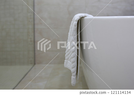 Foot towel in bathroom. Towel is hanging on edge of tub. Bathroom interior. Concept of hotel business and recreation. Foot towel in bathroom. Towel is hanging on edge of tub. Bathroom interior. Concept of hotel business and recreation. 121114134