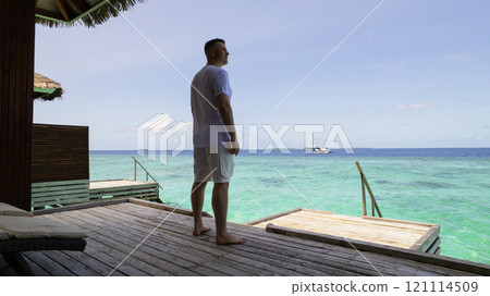 A guy in white clothes admires the turquoise ocean 121114509