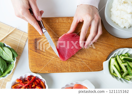 In the process of making sushi, preparing all the ingredients for sushi, the girl cuts the tuna. View from above. 121115162