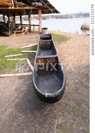 A handcrafted dugout canoe displayed near a lakeside workshop, showcasing traditional wooden craftsmanship A handcrafted dugout canoe displayed near a lakeside workshop, showcasing traditional wooden craftsmanship 121115174