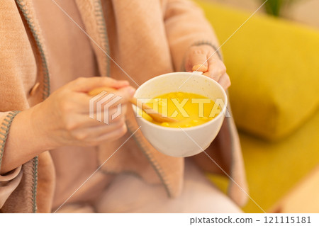 A middle-aged woman eating corn potage soup in the living room on a winter night A middle-aged woman eating corn potage soup in the living room on a winter night 121115181