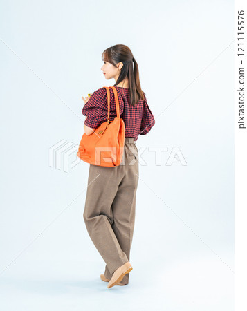 一位穿著休閒服的女性拿著智慧型手機行走的全身照片 一位穿著休閒服的女性拿著智慧型手機行走的全身照片 121115576