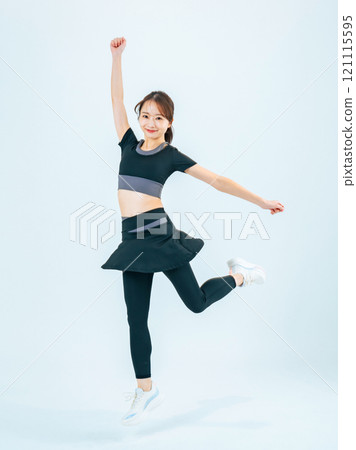Full body photo of a woman in sportswear jumping 121115595