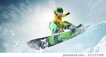 Snowboarder soaring high in vibrant gear, capturing thrill and freedom of winter sports with sparkling snow and towering mountains on background. 121115769