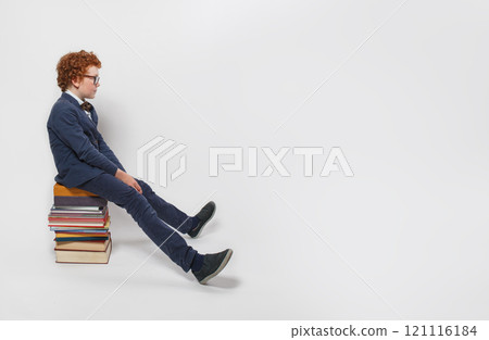 Portrait of redhead child school kid sitting on stack of books and thinking  121116184