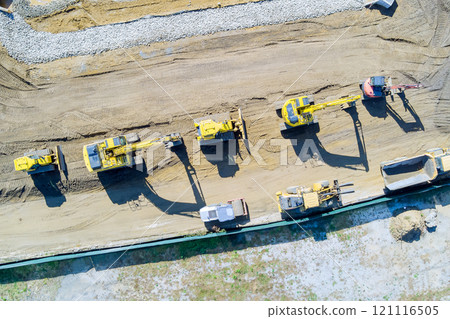 Heavy machinery is actively engaged in earth moving tasks at construction site excavators trucks are neatly arranged on soil, busy work environment. Heavy machinery is actively engaged in earth moving tasks at construction site excavators trucks are neatly arranged on soil, busy work environment. 121116505