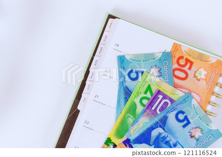 In order to plan financial future, Canadian dollar banknotes cash bills are collected placed in calendar planner. 121116524