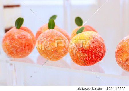 Brightly peach shaped desserts with sugar coating, small green leaves are beautifully arranged in inviting, perfect for dessert lovers. 121116531