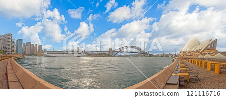 Panoramic view of Sydney Harbour with Opera House, Harbour Bridge, and cruise ship under dramatic clouds 121116716