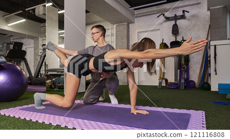 Physiotherapist guiding patient through bird dog exercise for balance and core strength improvement in a gym environment. Physiotherapist guiding patient through bird dog exercise for balance and core strength improvement in a gym environment. 121116808