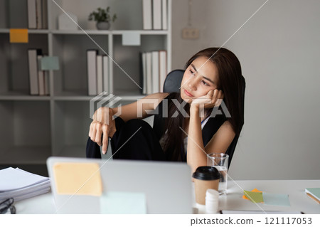 Stressed Office Worker Sitting at Desk with Laptop and Coffee in Modern Workspace 121117053