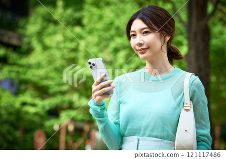 A stylish young woman operating a smartphone while shopping A stylish young woman operating a smartphone while shopping 121117486