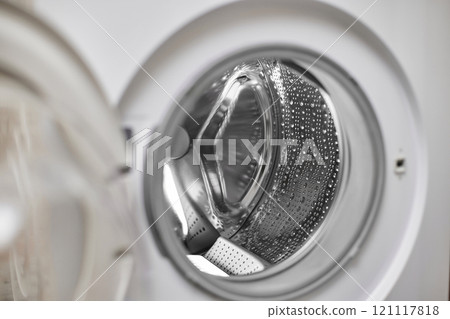 Open door of empty washing machine with metal drum in laundry room 121117818