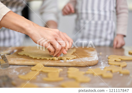 hands of mother and little child daughter cutting cookies of raw gingerbread dough in kitchen, Christmas traditions hands of mother and little child daughter cutting cookies of raw gingerbread dough in kitchen, Christmas traditions 121117847