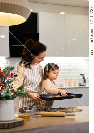 happy mother and little child daughter holding tray with gingerbread cookies in kitchen. Christmas time 121117855