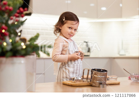 cute little child girl in apron baking cookies in the kitchen 121117866