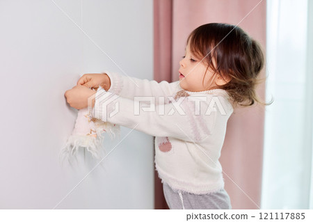 cute little child girl decorates her room before Christmas and hangs gnomes and snowmen on the door handle cute little child girl decorates her room before Christmas and hangs gnomes and snowmen on the door handle 121117885