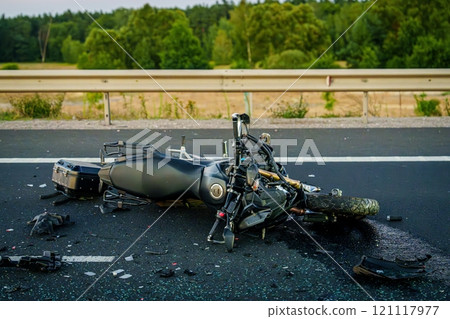 Black modern motorcycle laying on its side after an accident on an asphalt road. Black modern motorcycle laying on its side after an accident on an asphalt road. 121117977