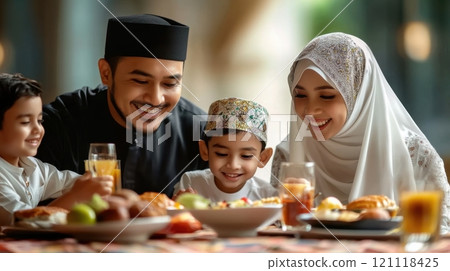Joyful family scene showing Muslim family enjoying meal together. Father, mother, son, and daughter dressed in traditional attire. 121118425