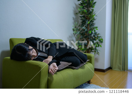 一個獨自生活的女人，她累了，睡在沙發上，工作時間很長。 121118446