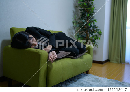 一個獨自生活的女人,她累了,睡在沙發上,工作時間很長。 一個獨自生活的女人,她累了,睡在沙發上,工作時間很長。 121118447